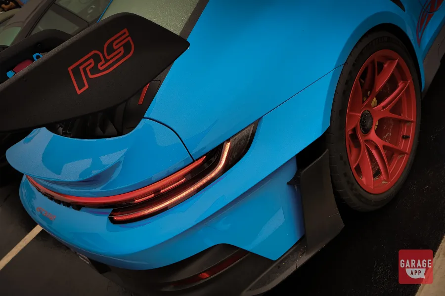 Porsche 911 GT3 RS parked at a Cars and Coffee event, showcasing its aerodynamic design and track-focused performance while being documented in a digital garage.