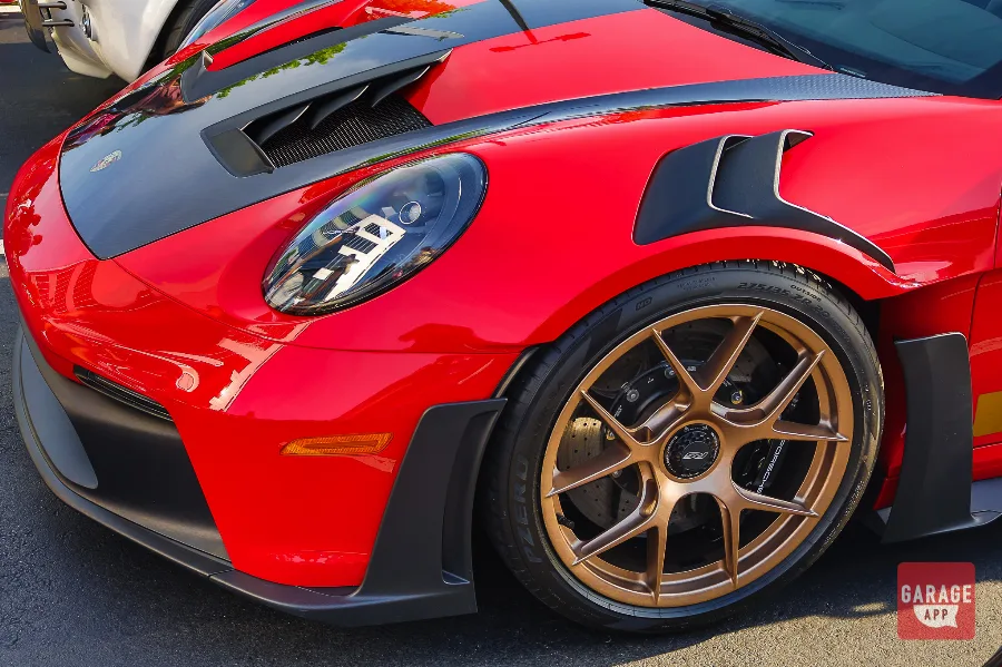 Close-up of a red Porsche 911 GT3 RS showing carbon fiber aero components and bronze wheels.