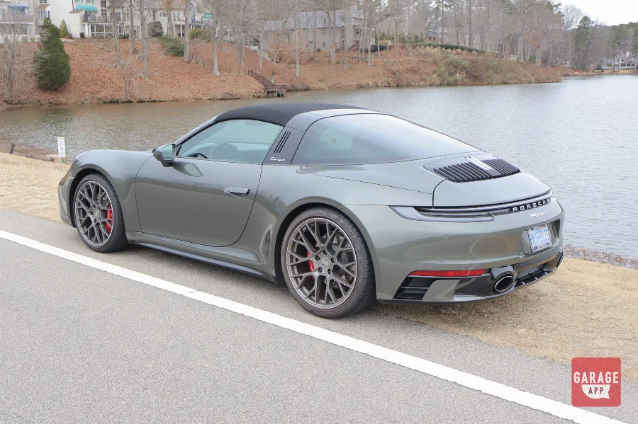 Rear three-quarter angle of a 992.1 Porsche 911 Targa 4S in Aventurine Green Metallic highlighting the full-width LED taillight and Targa roof.