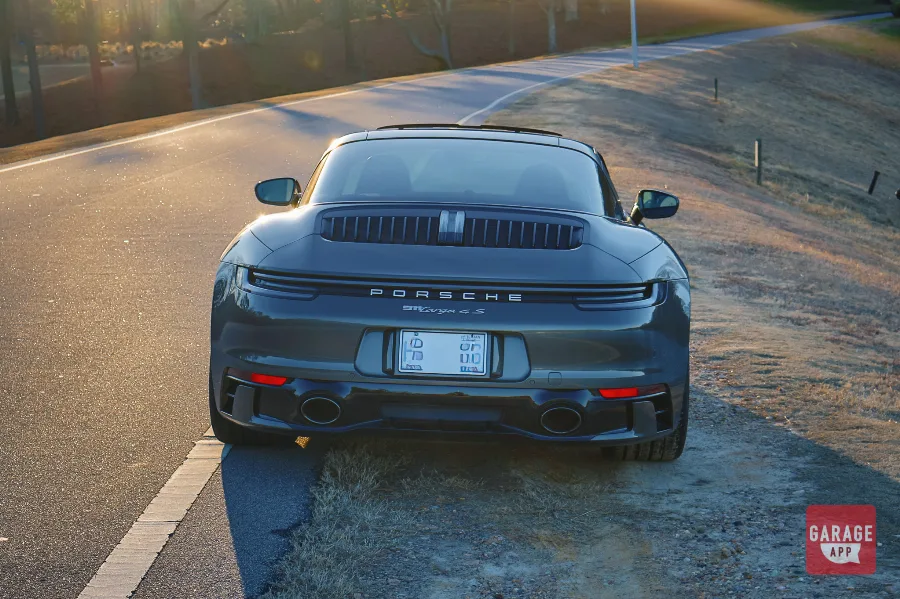 Rear view of a 992.1 Porsche 911 Targa 4S finished in Aventurine Green Metallic featuring dual exhaust tips and the full-width LED light bar.