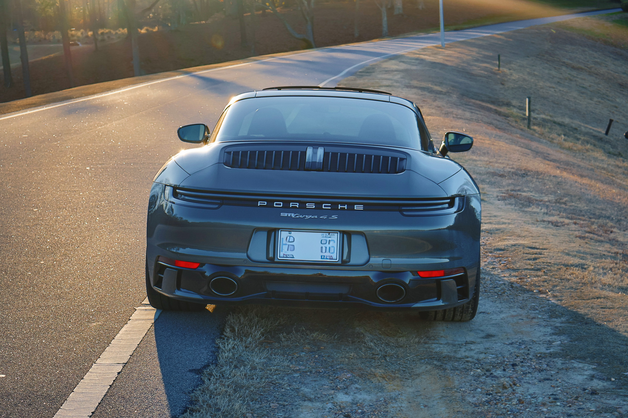 Rear view of a 992.1 Porsche 911 Targa 4S finished in Aventurine Green Metallic featuring dual exhaust tips and the full-width LED light bar.