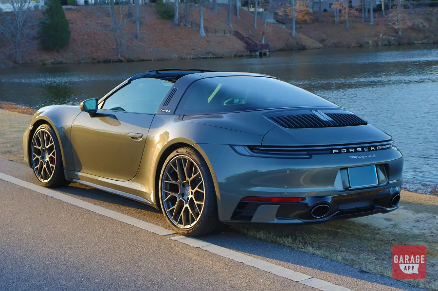 Rear three-quarter view of a 992.1 Porsche 911 Targa 4S in Aventurine Green Metallic with the automatic Targa roof in motion.