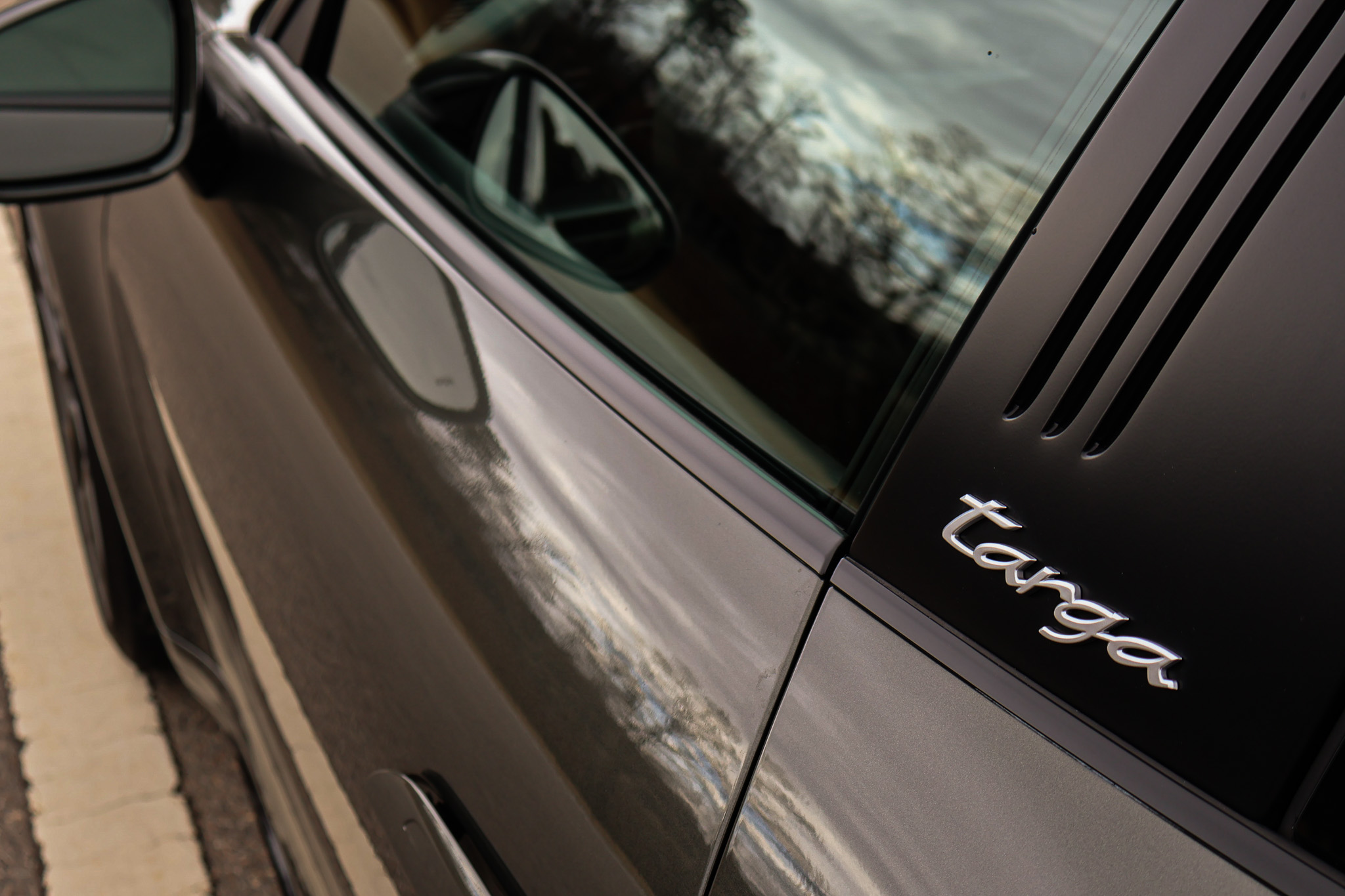 Close-up of the Targa script on the brushed roll bar of a 992.1 Porsche 911 Targa 4S finished in Aventurine Green Metallic.
