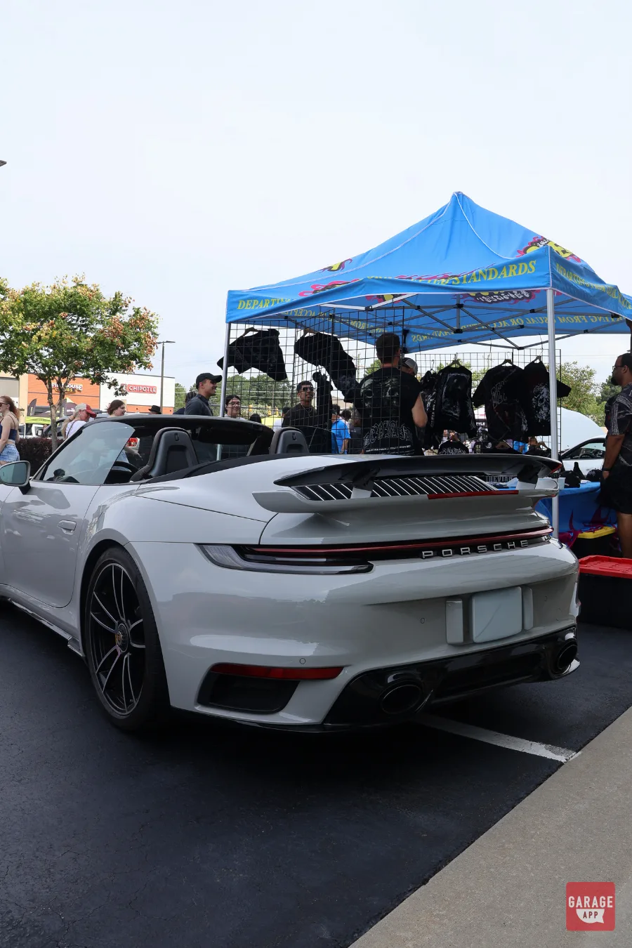 White Porsche 911 Turbo S Cabriolet parked near vendor tent at car meet