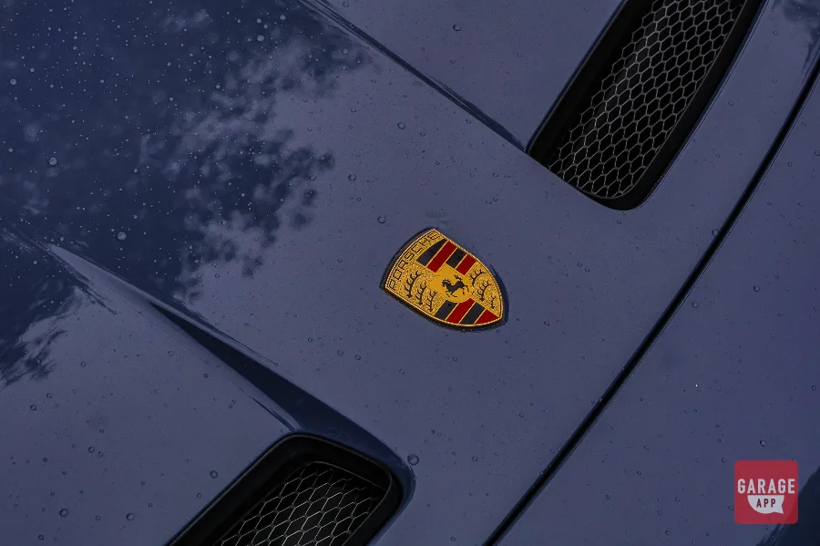 Porsche crest hood badge close-up on GT3 Touring in rain, raindrops on paint