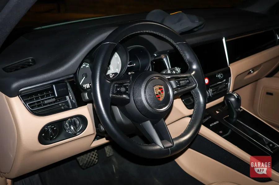 Porsche Macan S interior at night showing leather steering wheel and digital dashboard