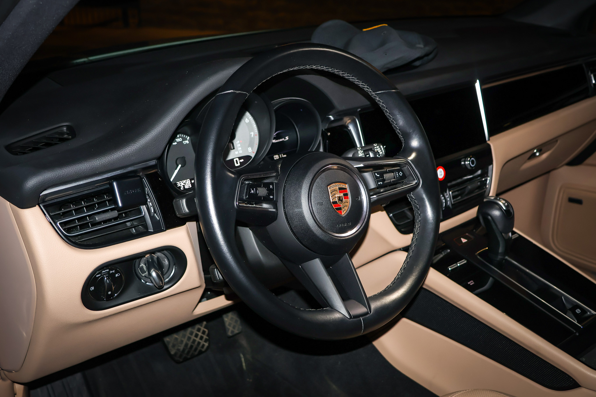 Porsche Macan S interior at night showing leather steering wheel and digital dashboard