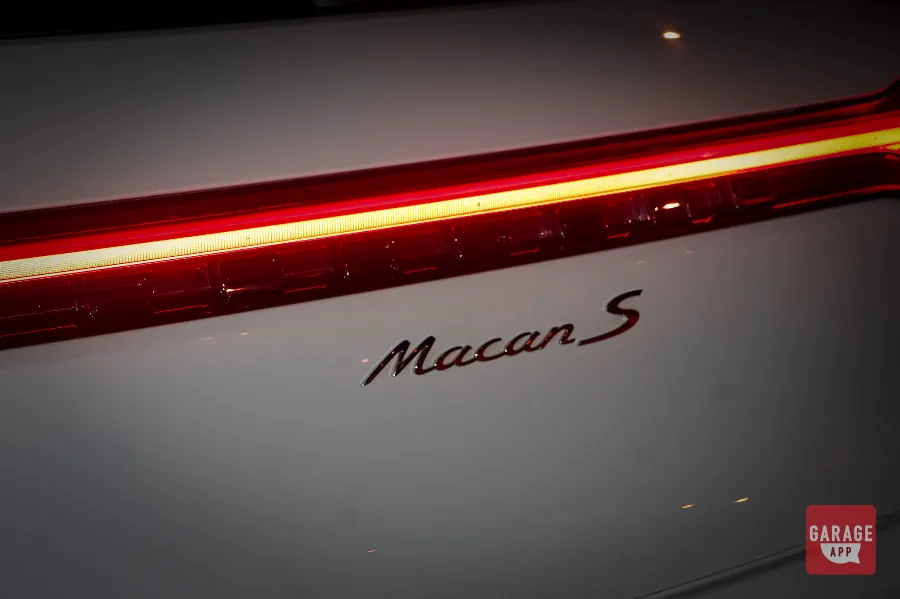 Illuminated LED taillight strip beside Macan S badge on white Porsche
