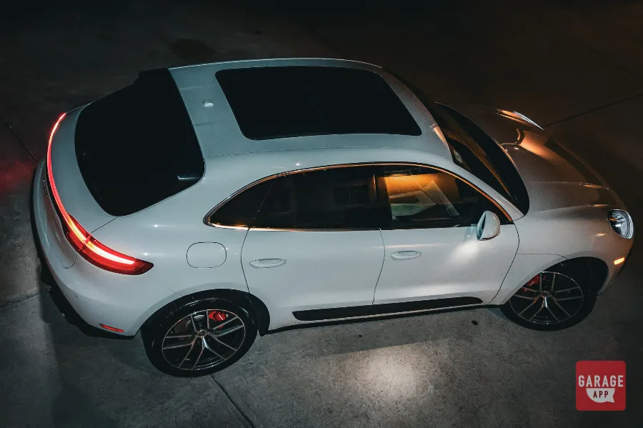 Aerial side view of white Porsche Macan S at night showing panoramic sunroof