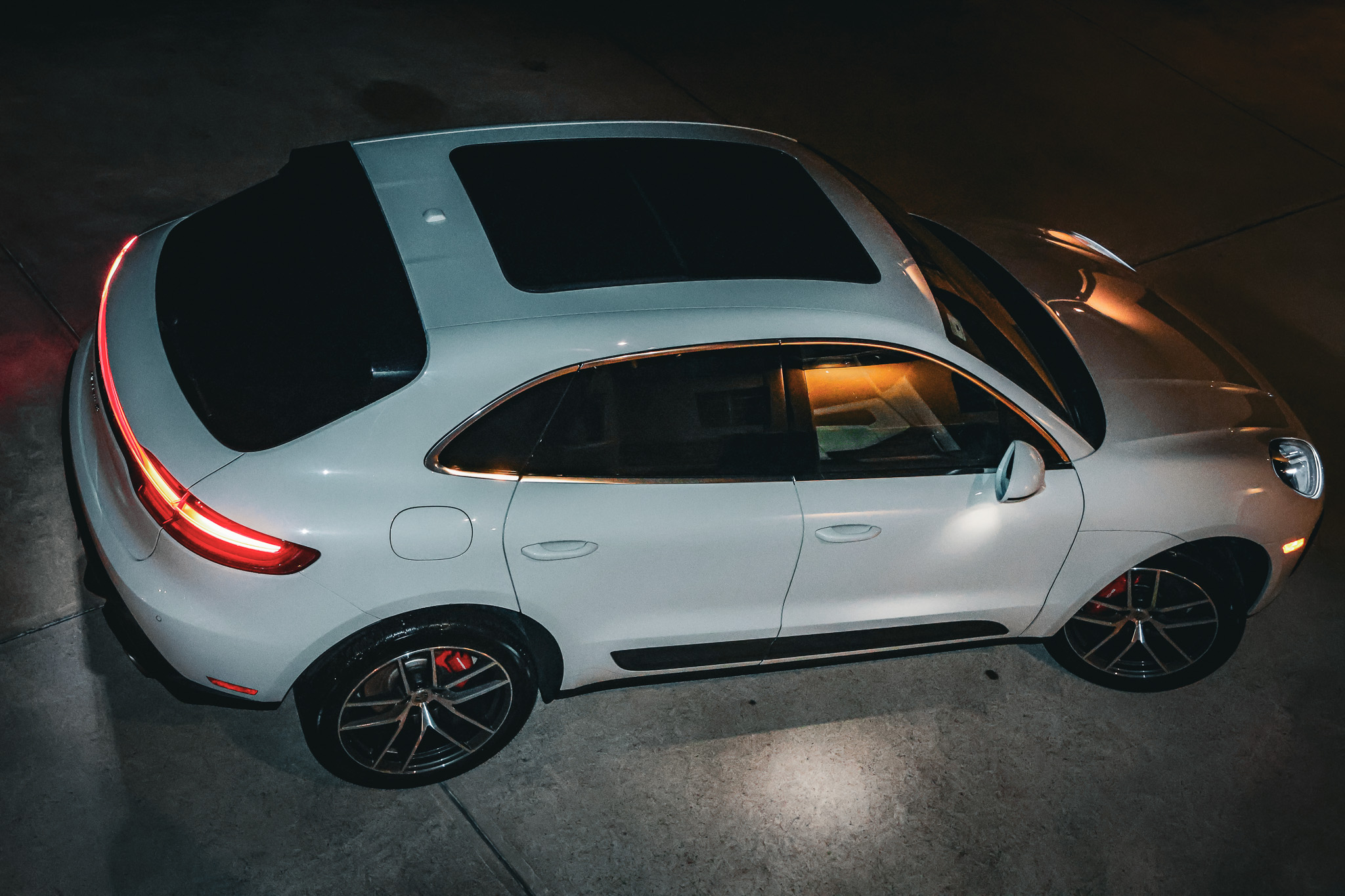 Aerial side view of white Porsche Macan S at night showing panoramic sunroof