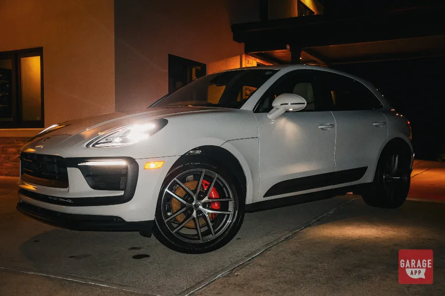 White Porsche Macan S front three-quarter view with LED headlights on at night