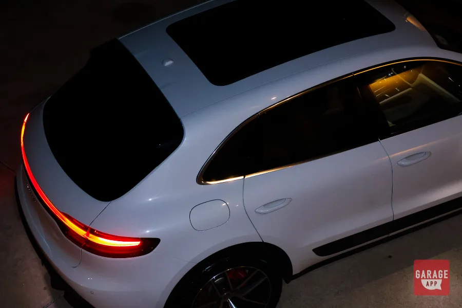 Aerial rear quarter view of white Macan S showing taillight and window trim at night