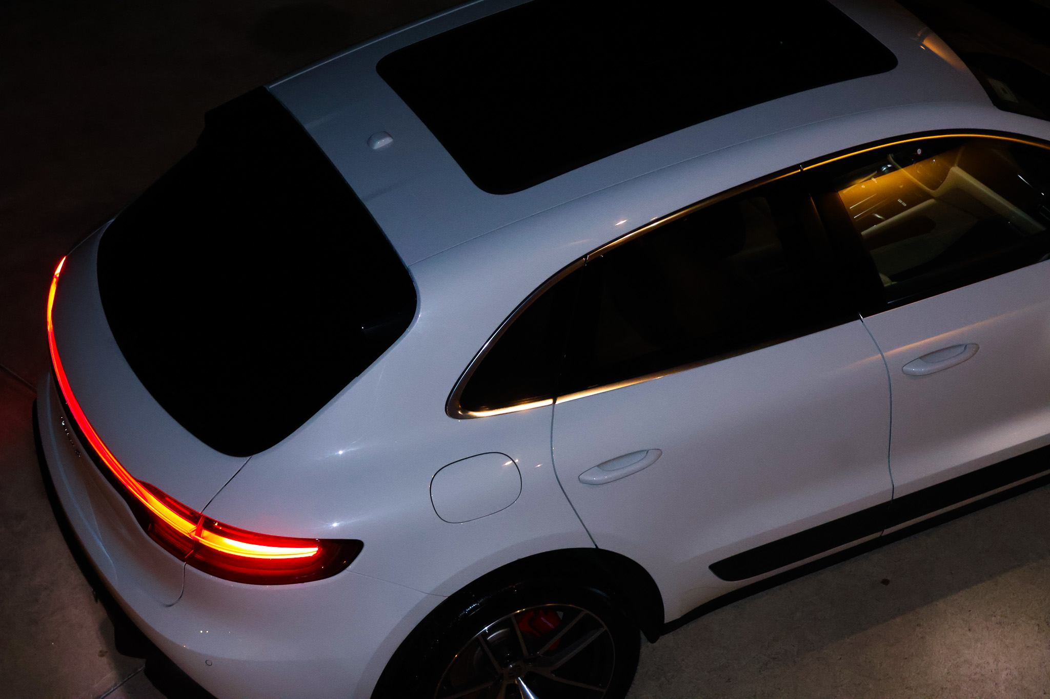 Aerial rear quarter view of white Macan S showing taillight and window trim at night