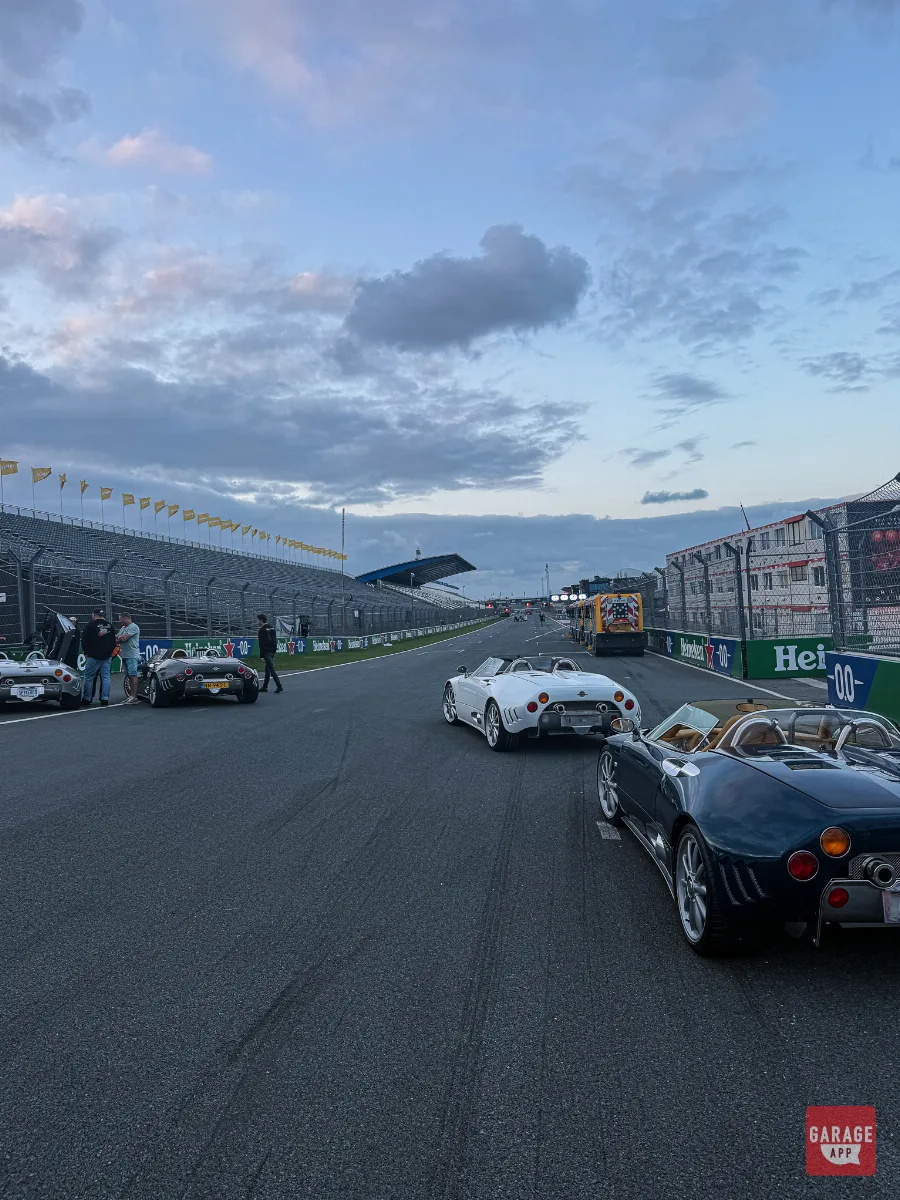 White and black Spyker C8 parade cars on empty Zandvoort straight at dusk