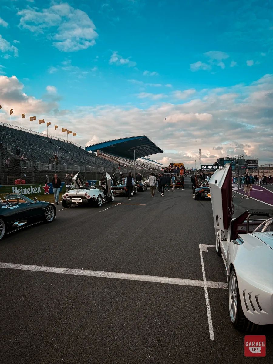 Spyker C8 parade cars with doors up lined up on Zandvoort grid at sunset