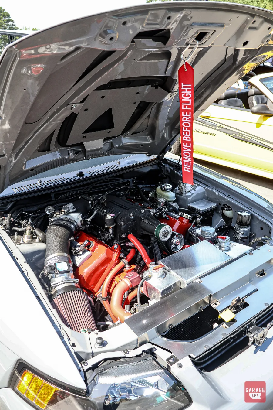 Detailed view of a supercharged V8 engine installed in a Ford Mustang Mach 1 during Fuquay-Varina Cars and Coffee.