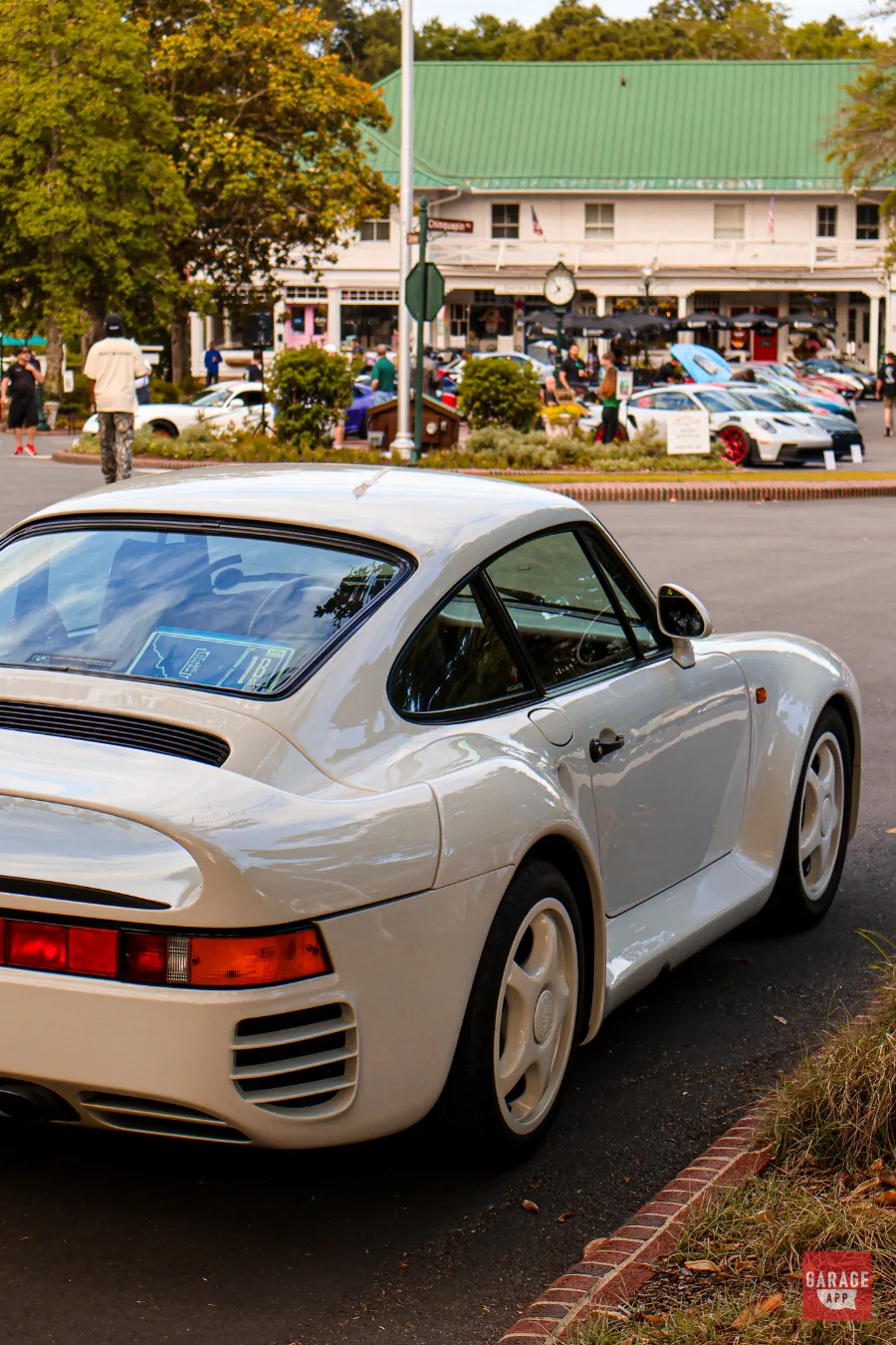 White Porsche 959 parked at Hagerty Cars & Caffeine in Pinehurst with classic and modern Porsche sports cars gathered in the background.