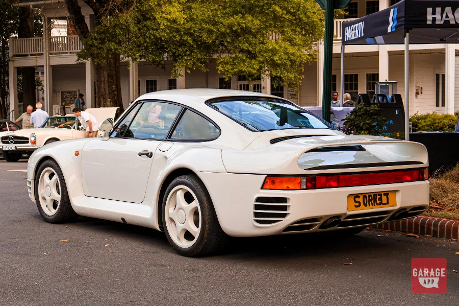 Rear three-quarter view of a white Porsche 959 showing its integrated rear wing and twin exhaust system during Hagerty Cars & Caffeine in Pinehurst.